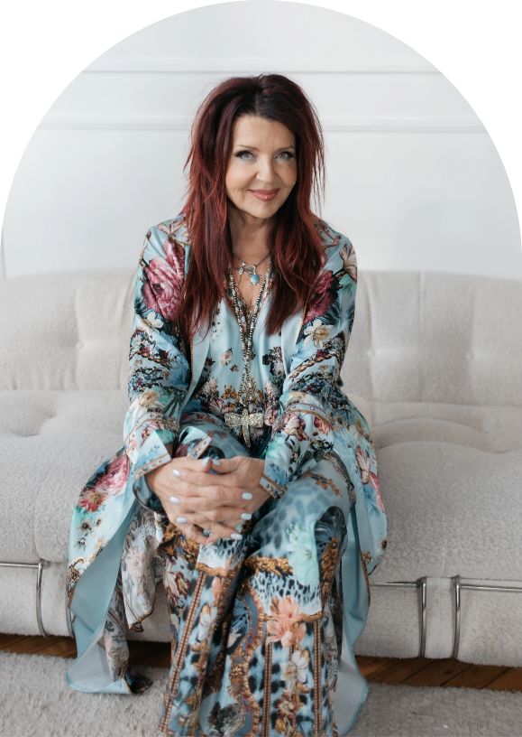 Colette Baron-Reid sitting on a beige sofa and smiling