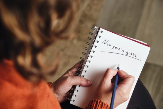 Unrecognizable,Woman,From,Behind,In,Orange,Sweater,Holds,A,Pencil
