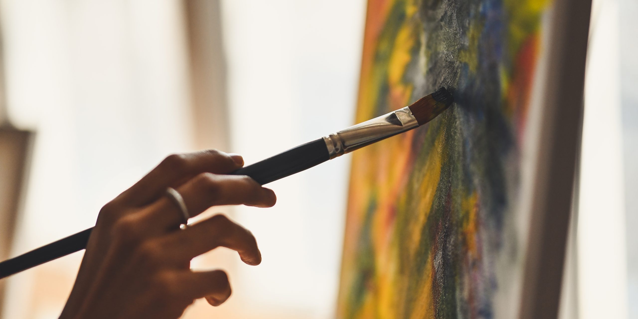 Cropped image of artist woman’s hand drawing an oil color on canvas by paint brush at the modern art studio. Young artist/Painter concept.