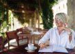Mature senior woman writing to notebook or diary at a cafe