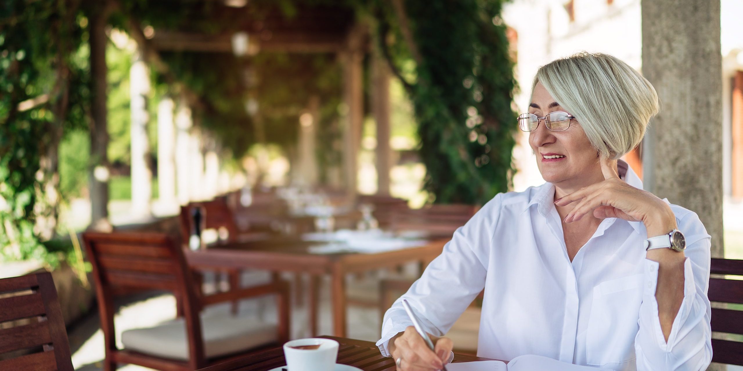 Mature senior woman writing to notebook or diary at a cafe